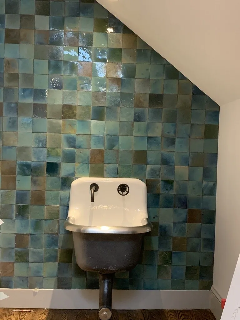 Glazed green tile wall behind a wall-mounted sink in a Beals Street condominium