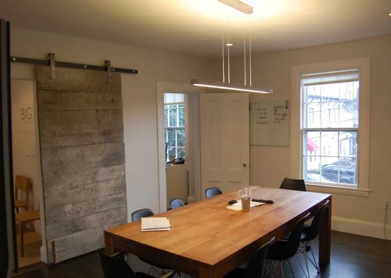 Meeting room with a reclaimed barn door and a long wood table